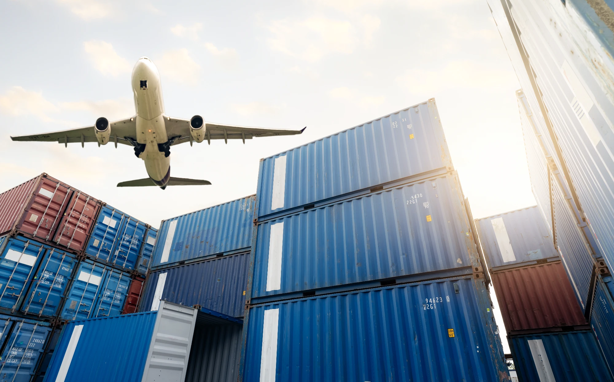 Samolot cargo lecący nad kontenerami
